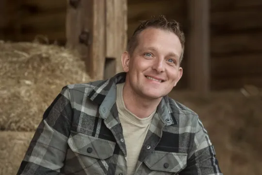 een man in geruite blouse in het hooi