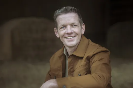 een man poseert in een stal