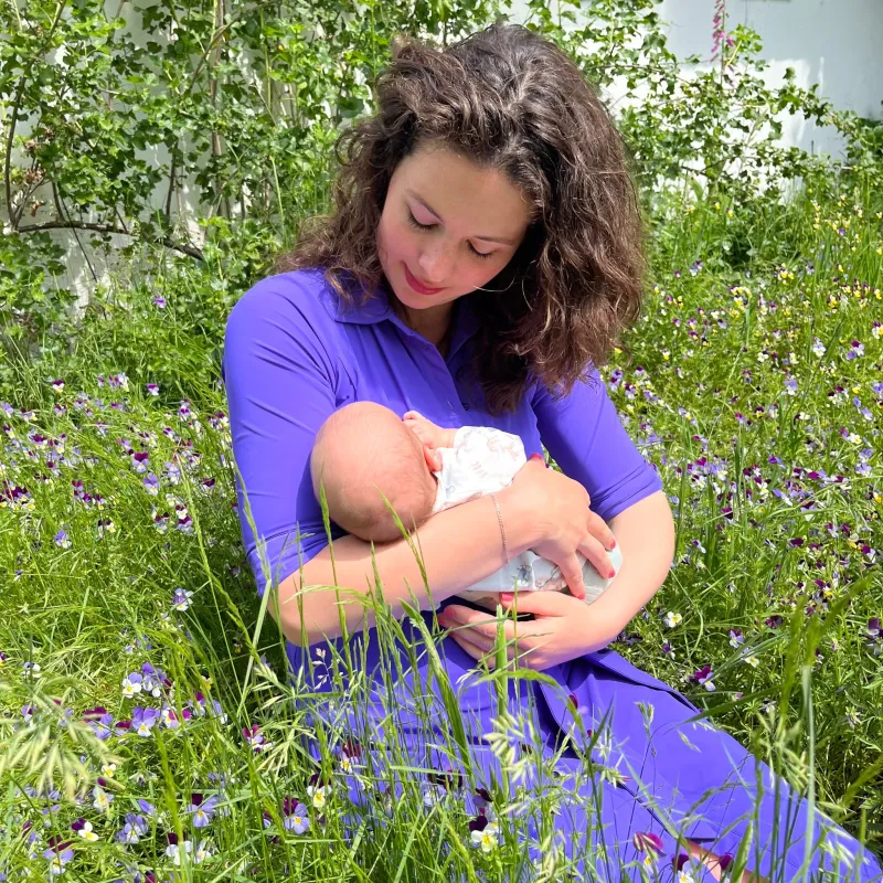 een vrouw zit in het gras met een baby