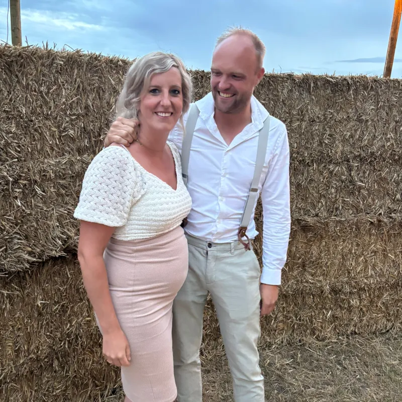 Janine en Sander poseren samen voor hooibalen op een bruiloft