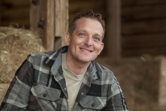 een man in geruite blouse in het hooi