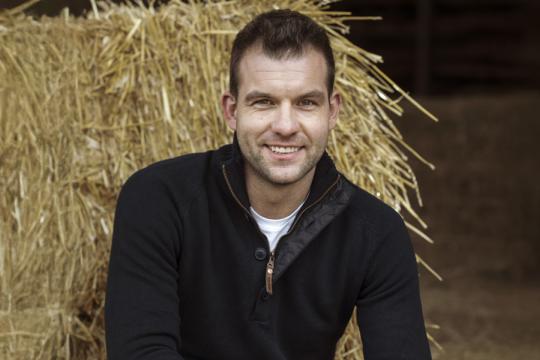 een man poseert in een stal