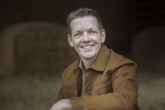 een man poseert in een stal