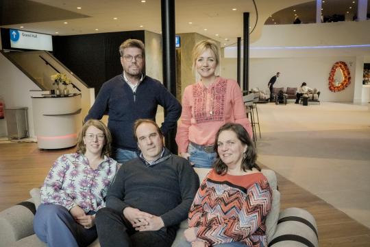 een groepsfoto met vijf mensen