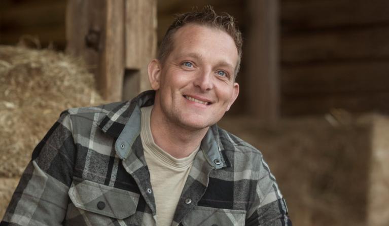 een man in geruite blouse in het hooi