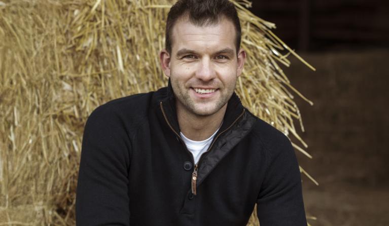 een man poseert in een stal