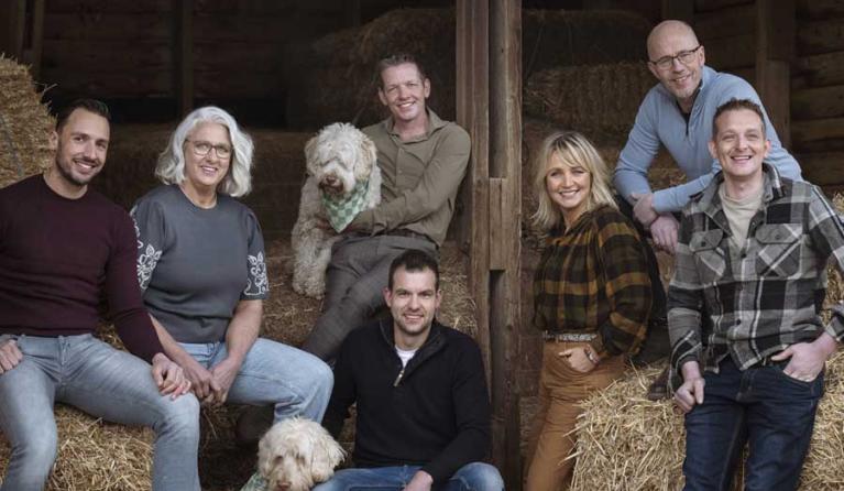 een groep mensen poseert in een stro-opslag