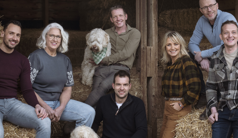 een groep mensen poseert in een stro-opslag