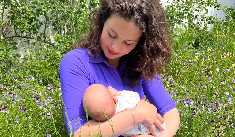 een vrouw zit in het gras met een baby