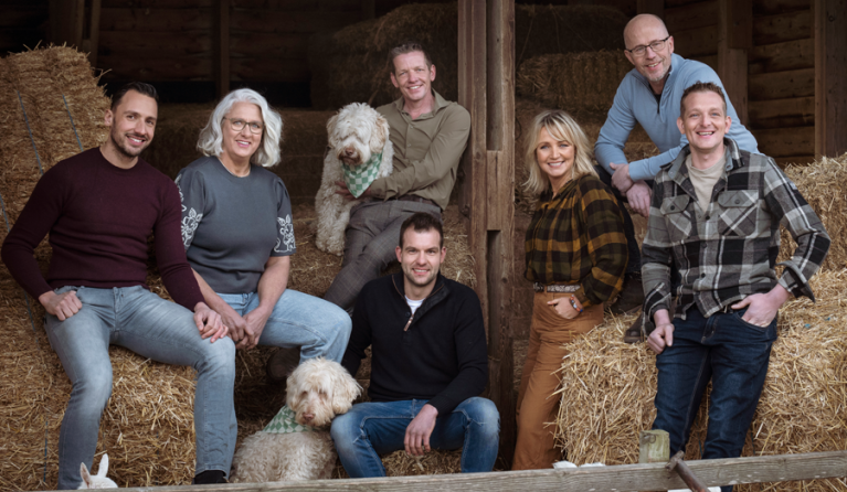 een groep mensen poseert in een stro-opslag