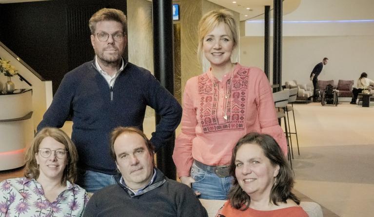 een groepsfoto met vijf mensen