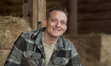 een man in geruite blouse in het hooi