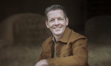 een man poseert in een stal