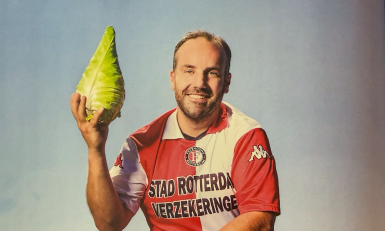 Een jongen met een Feyenoord shirt houdt een kool in de lucht