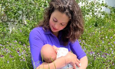 een vrouw zit in het gras met een baby