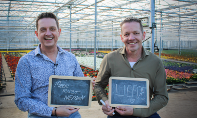 twee mannen in een kas met een krijtbordje in hun handen