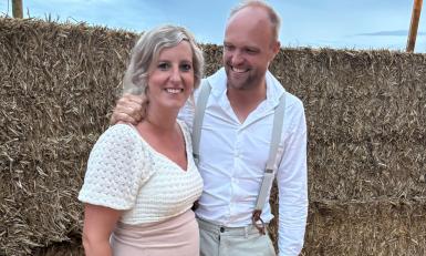 Janine en Sander poseren samen voor hooibalen op een bruiloft